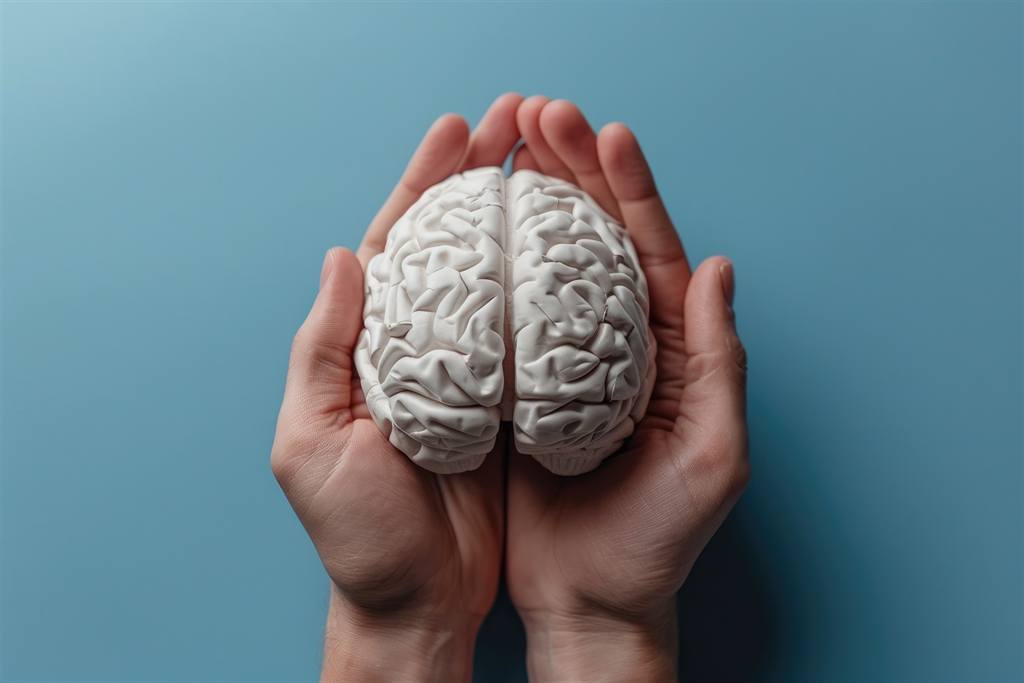 Mãos segurando um cérebro de papel, representando o cuidado com a saúde mental